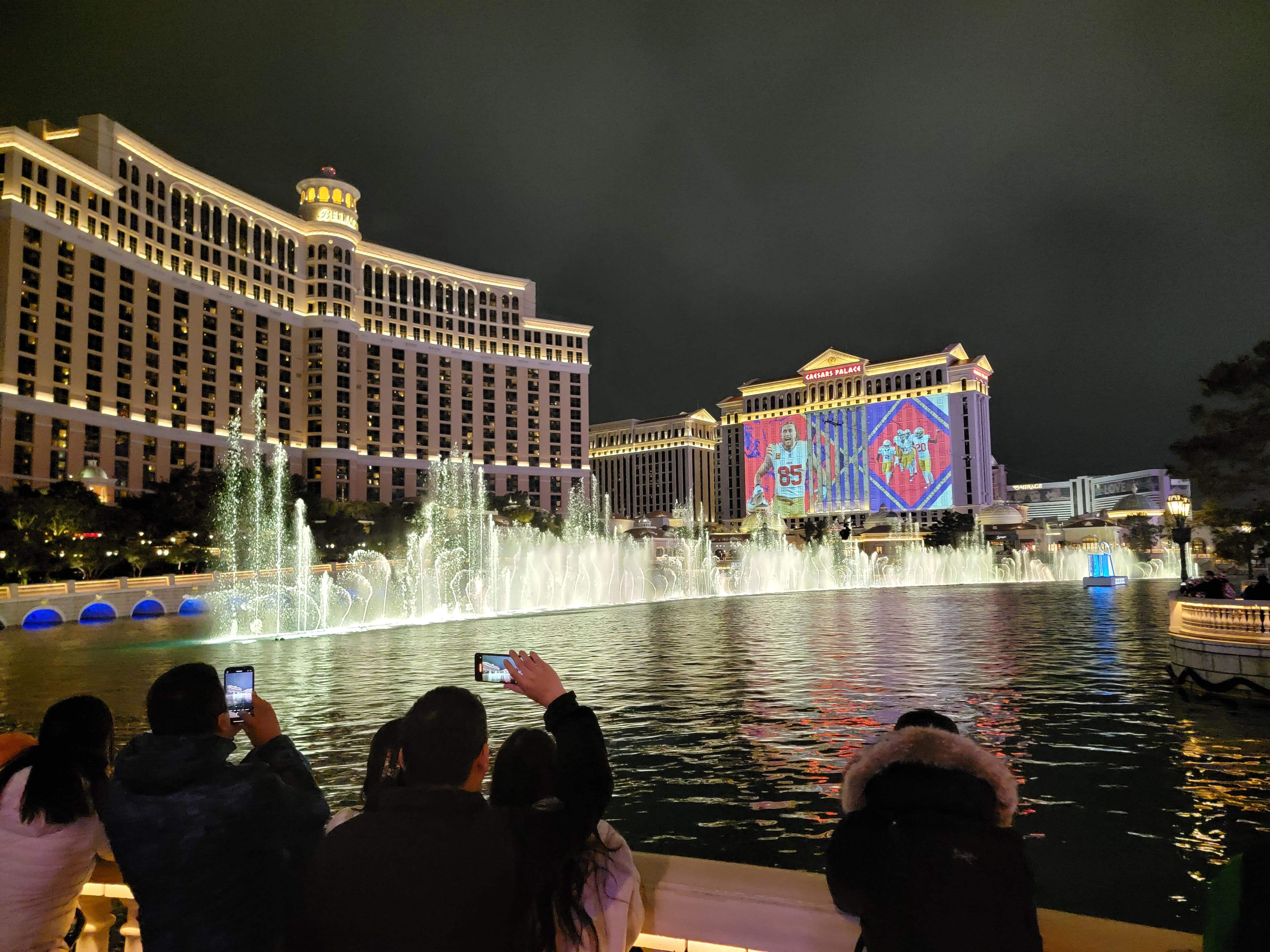 People taking pictures of Screenberry-driven projection mapping on the Caesars Palace facade in Las Vegas