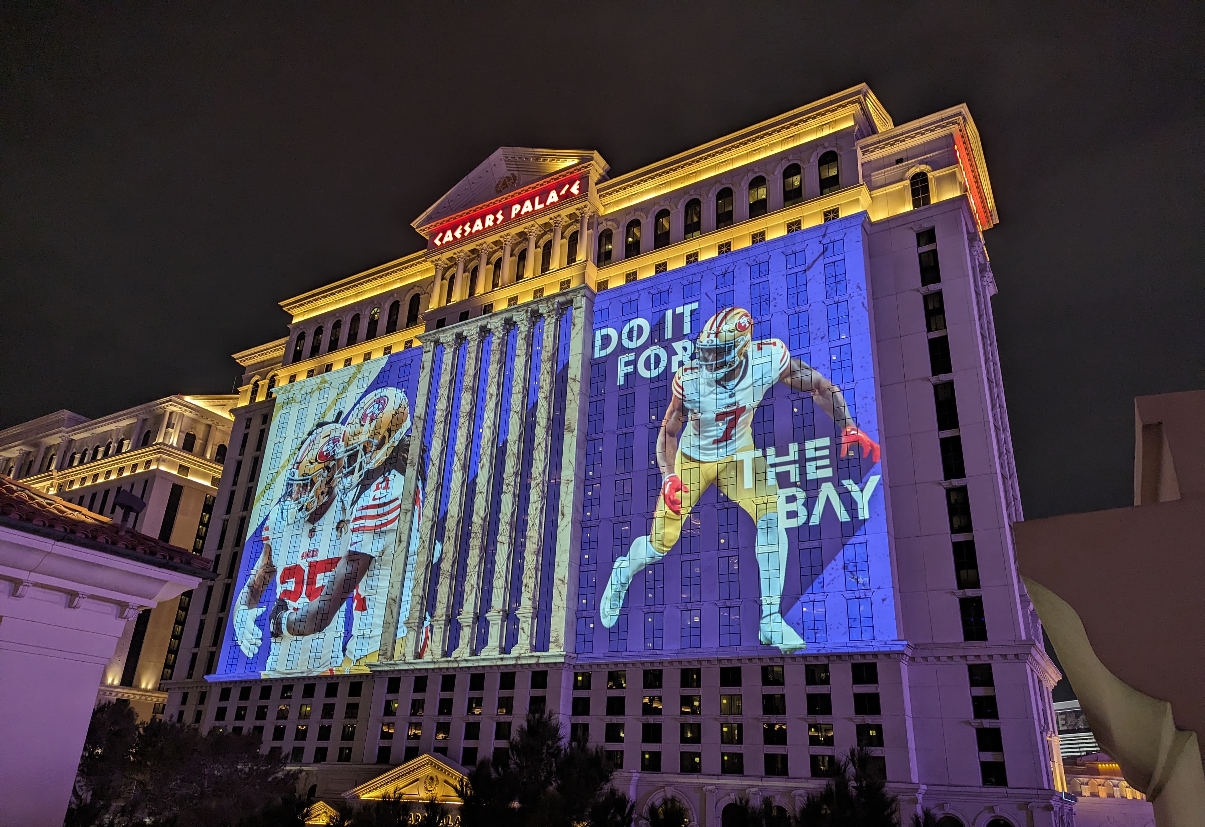 Screenberry-driven video mapping show featuring American football players projected onto the Caesars Palace facade during Super Bowl week in Las Vegas
