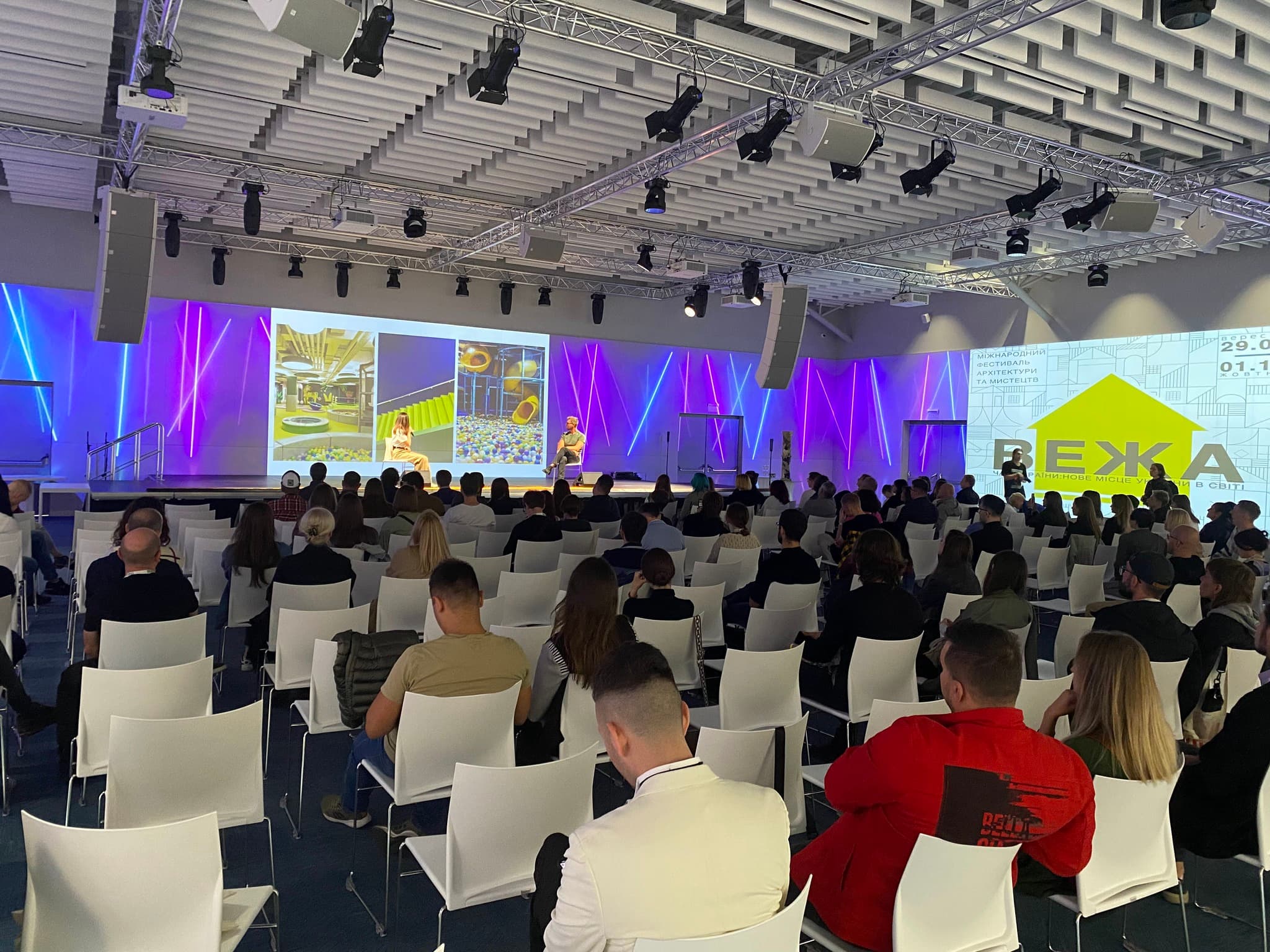People sitting on chairs at an event venue with bright 270-degree projections on walls